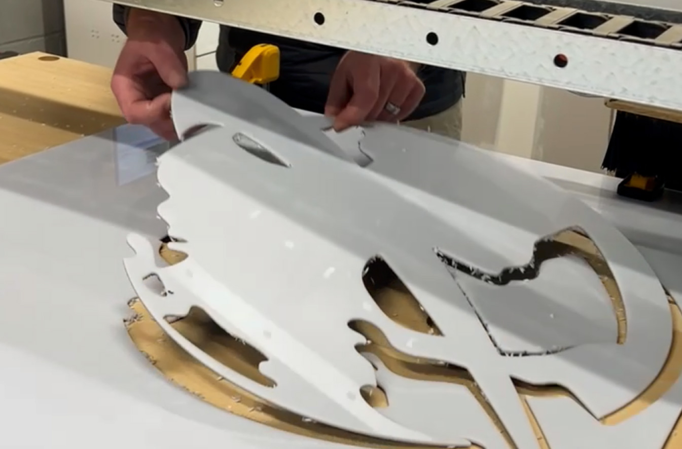 A man releasing 3/16 inch polycarbonate logo from the cnc