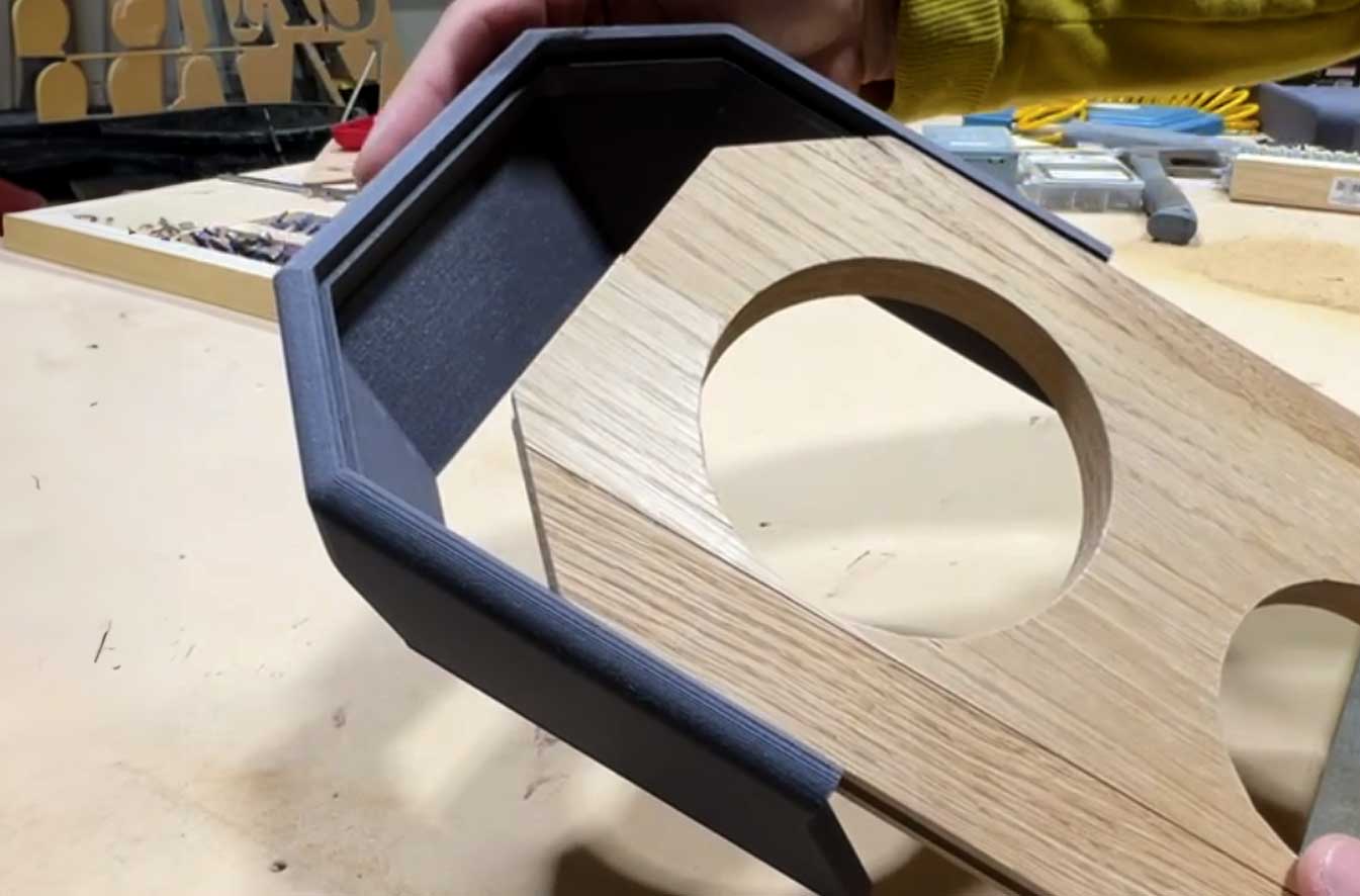 A man holding a custom 3d printed part, checking fitment as it slides onto another custom part